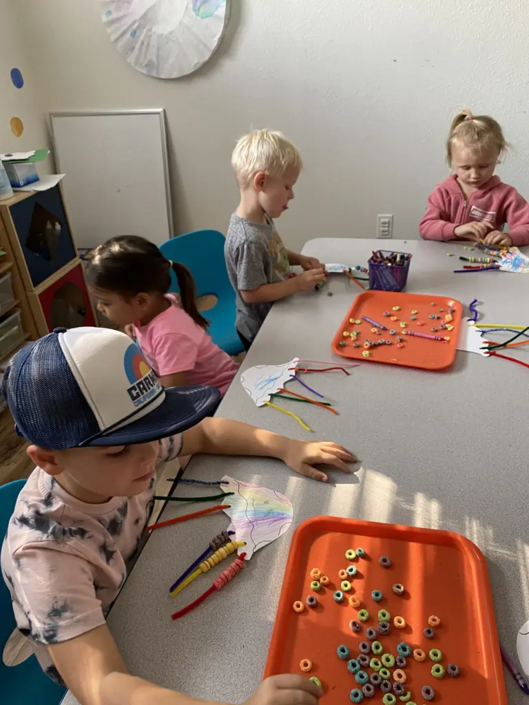 Children work on dot art and colouring with markers at a sunny classroom table